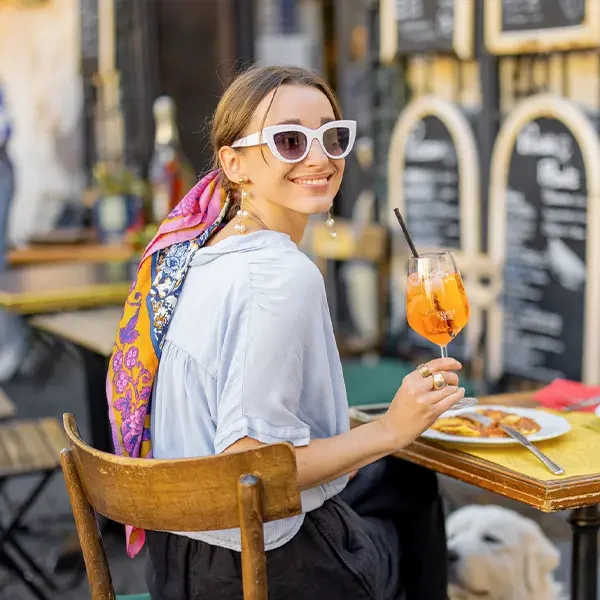 Frau isst italienische Pasta und trinkt Aperol Spritz im Restaurant auf der Straße in Rom. Busreisen nach Italien.