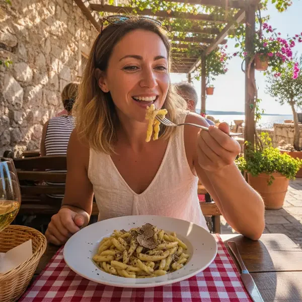 Eine junge Frau genießt in einer kroatischen Konoba das Gericht Fuži, während einer Busfahrt in Kroatien.