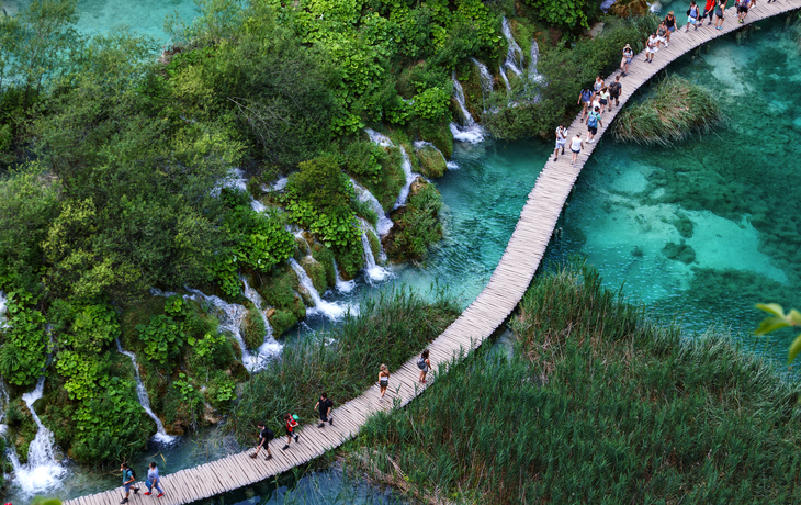 Luftaufnahme eines hölzernen Wanderwegs neben Wasserfällen im Nationalpark Plitvicer Seen