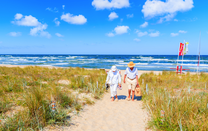 Ein paar Leute gehen vom Strand im Sommerurlaubsort Baabe zwischen Sanddünen,Ostsee,Deutschland. Rügen ist aufgrund seiner Sandstrände ein beliebtes Touristenziel.