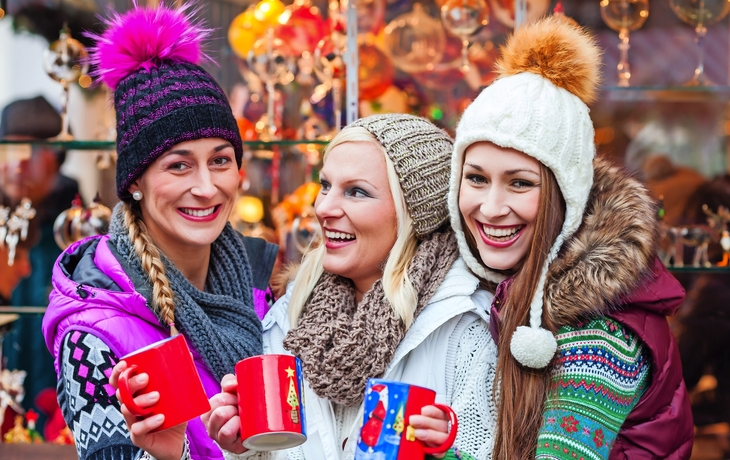 Freunde trinken Glühwein auf Weihnachtsmarkt