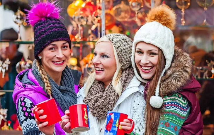 Freunde trinken Glühwein auf Weihnachtsmarkt