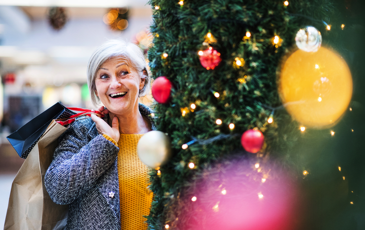 Ein Porträt der älteren Frau mit Papiertüten im Einkaufszentrum am Weihnachten.