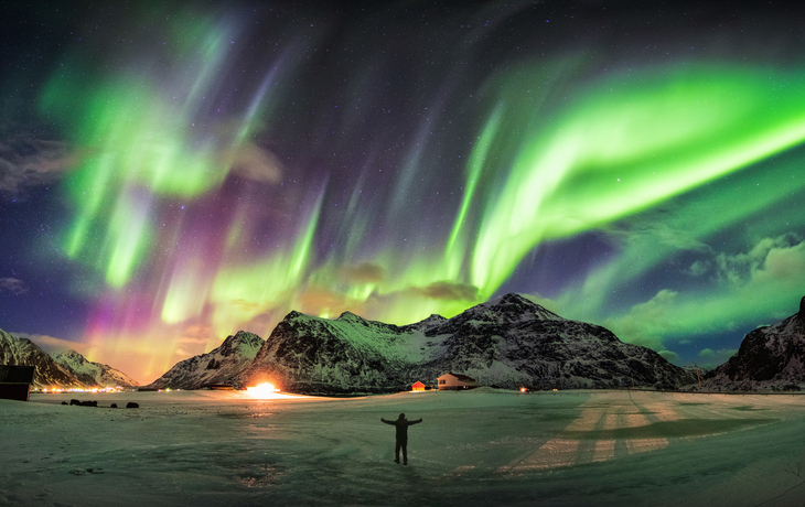Aurora borealis (Nordlichter) über Berg mit einer Person