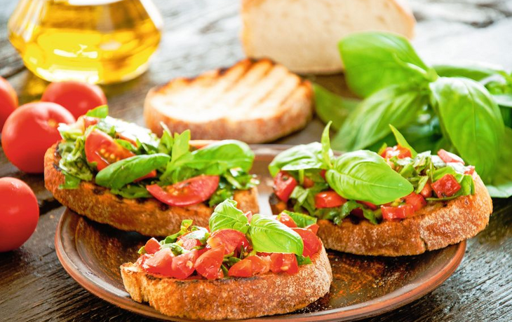 Italian bruschetta with chopped vegetables, herbs and oil on gr
