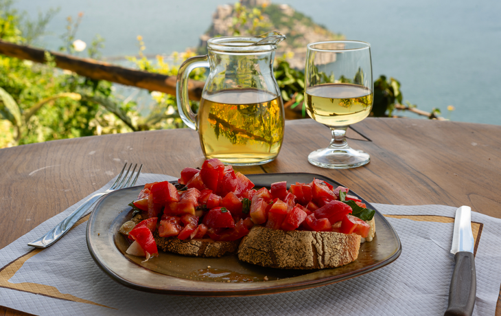 Italienische Bruschetta und Weißwein vor dem Hintergrund der aragonesischen Burg auf der Insel Ischia, Italien