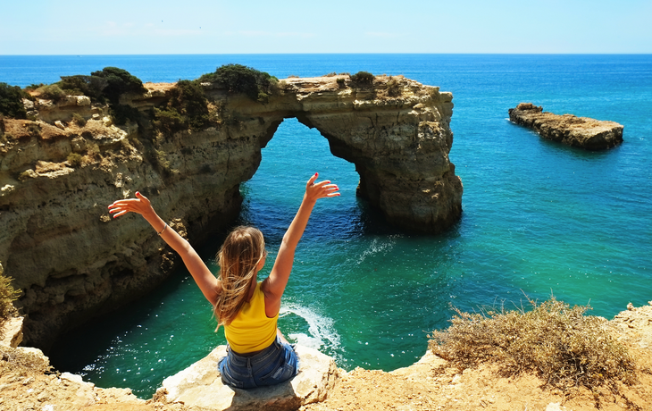 Frau genießt den Panoramablick von oben auf die Küste der Algarve