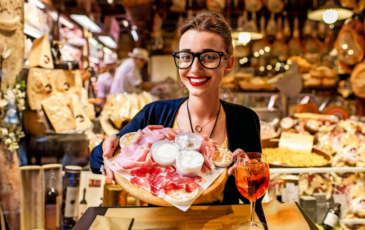 Frau mit traditionellem Aperitif und italienischer Vorspeisenplatte