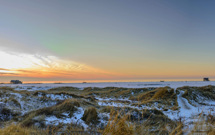 Panoramablick auf die Dünenlandschaft mit Stelzenhäusern im Winter in St. Peter-Ording