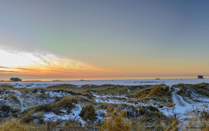 Panoramablick auf die Dünenlandschaft mit Stelzenhäusern im Winter in St. Peter-Ording