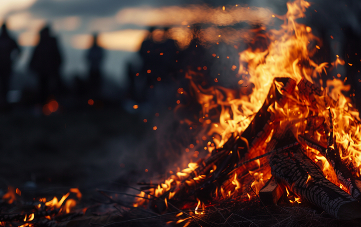 Lagerfeuer mit Menschen im Hintergrund