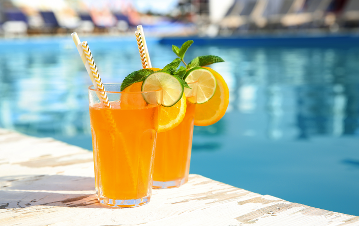 Erfrischender Cocktail in Gläsern in der Nähe des Außenpools an einem sonnigen Tag