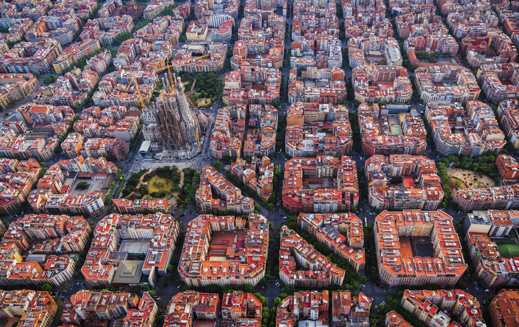 Luftaufnahme von Barcelonas schachbrettartig angelegtem Stadtviertel Eixample und der Kathedrale Sagrada Familia