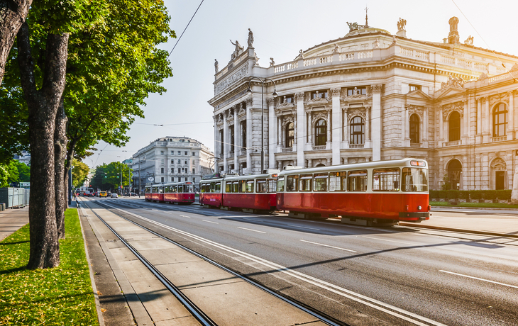 die Wiener Ringstraße mit dem Burgtheater und einer Straßenbahn bei Sonnenaufgang