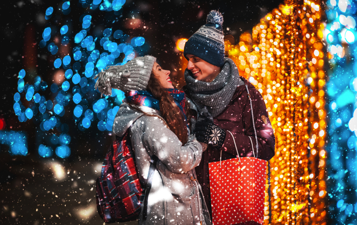 Paar mit Geschenktüte auf Weihnachtsmarkt