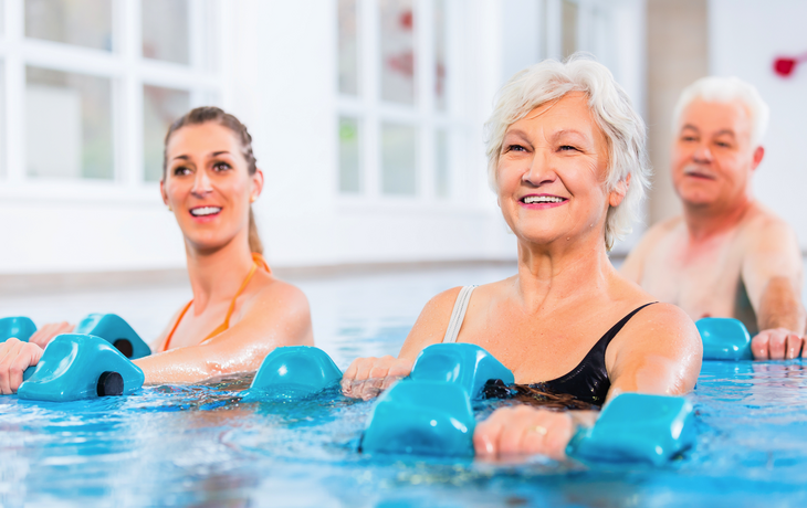 Junge und ältere Menschen bei der Wassergymnastik-Physiotherapie mit Hanteln