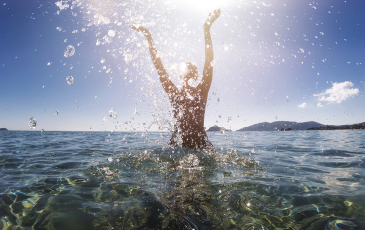 junge Frau steht im Meer und spritzt mit Wasser