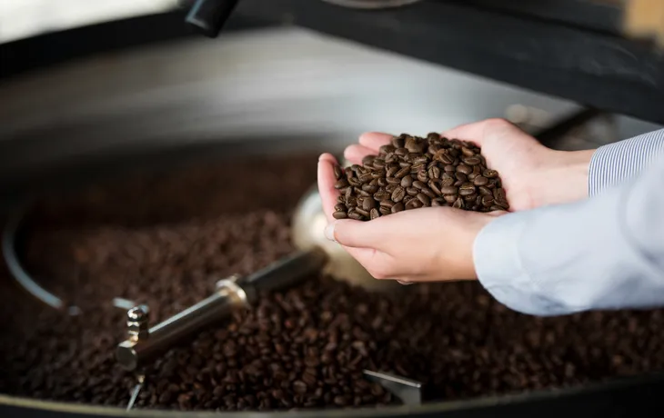 Frau in der Rösterei hält Kaffeebohnen in der Hand