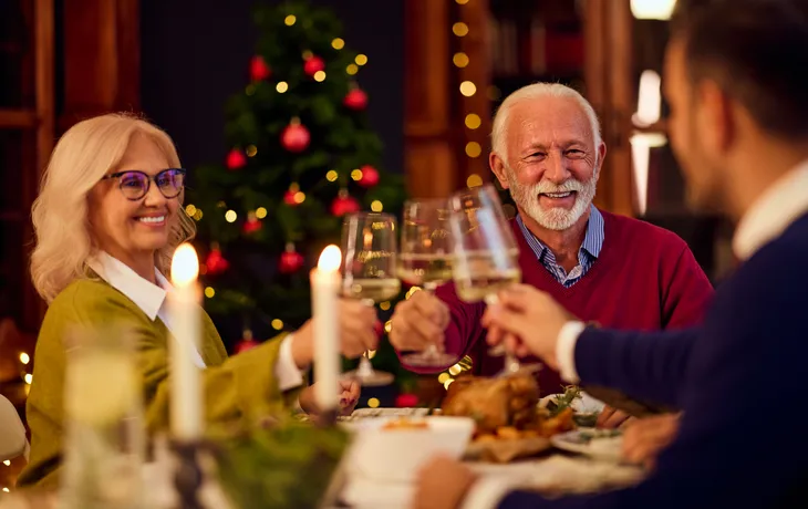 Mit der Familie beim Weihnachtsessen am Baum anstoßen, ein gemütliches Fest