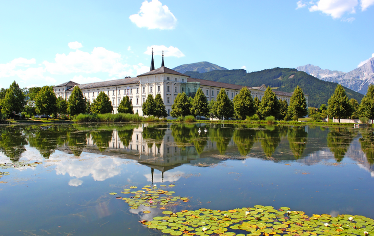 Stift Admont vor blauem Himmel spiegelt sich im Stiftssee