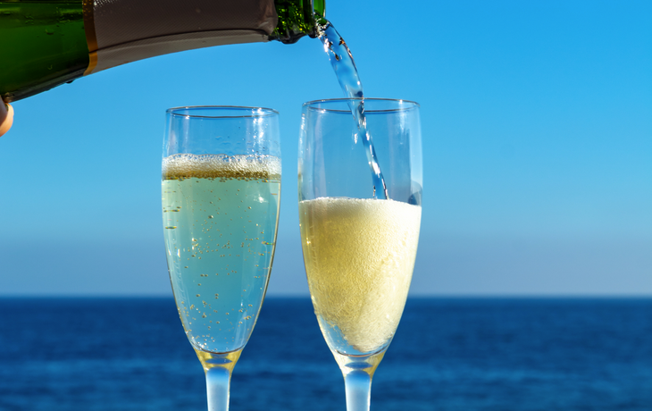 Kellner, der auf der Außenterrasse mit Meerblick Champagner, Prosecco oder Cava in zwei Gläser einschenkt
